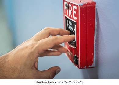 Activate fire alarm trigger system which is installed on building wall. Human action scene photo, selective focus.