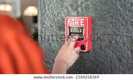 Activate fire alarm trigger system which is installed on granite wall of the building. Human action scene photo, selective focus.