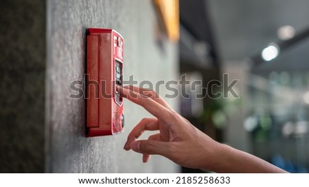 Activate fire alarm trigger system which is installed on granite wall of the building. Human action scene photo, selective focus.