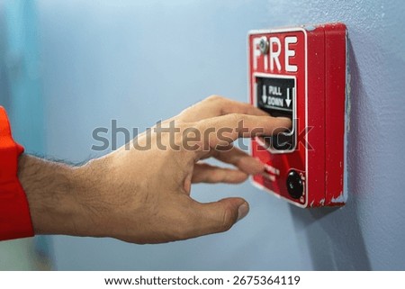 Activate fire alarm trigger system which is installed on building wall. Human action scene photo, selective focus.