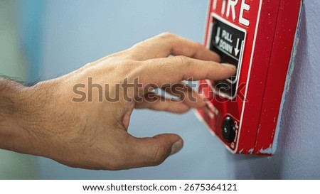 Activate fire alarm trigger system which is installed on building wall. Human action scene photo, selective focus.