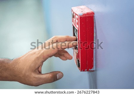 Activate fire alarm trigger system which is installed on building wall. Human action scene photo, selective focus.