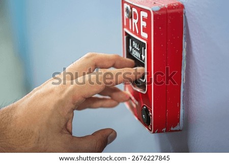 Activate fire alarm trigger system which is installed on building wall. Human action scene photo, selective focus.