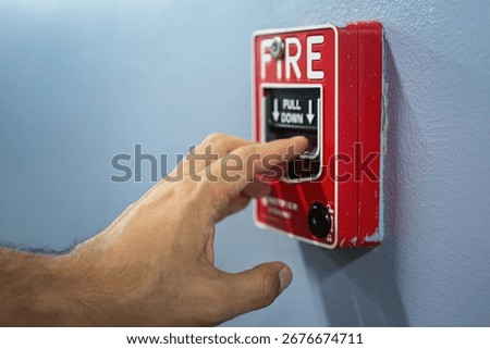 Activate fire alarm trigger system which is installed on building wall. Human action scene photo, selective focus.