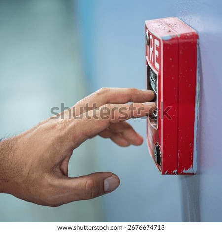 Activate fire alarm trigger system which is installed on building wall. Human action scene photo, selective focus.