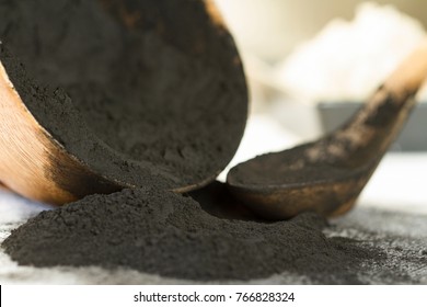 Activated Charcoal Powder Spilling Out of a Wooden Bowl