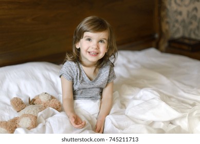 Active Adorable Child Awake, Lying In Bed, Soft White Bed Sheets. Day Of Protection Of Children. World Smile Day.	
