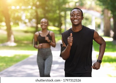 Active African American Couple Jogging In Summer Park, Enjoying Healthy Lifestyle And Training Outdoors, Selective Focus With Copy Space