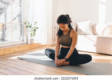 Active african american pregnant woman practicing yoga, sitting in butterfly or konasana pose, stretching muscles on mat, doing prenatal exercises for healthy pregnancy and prepare body for childbirth
