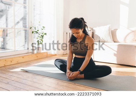 Active african american pregnant woman practicing yoga, sitting in butterfly or konasana pose, stretching muscles on mat, doing prenatal exercises for healthy pregnancy and prepare body for childbirth