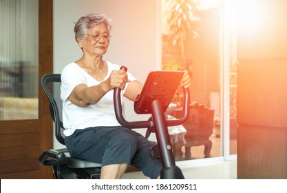 Active Asia Senior Old Woman People Training Exercise On Stationary Bike For Fit Healthy At Home Gym.