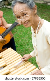 Active Asian Elderly Woman Playing Traditional Music Instrument