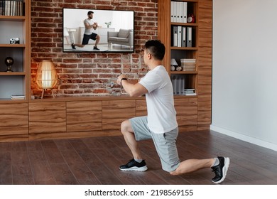 Active Asian Mature Man Exercising At Home And Watching Sport Channel And Fitness Workout Program On TV. Sport Motivation And Healthy Lifestyle Concept