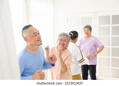 Active Asian Senior Group Mix With Man And Woman Exercise By Dancing Together At Home With Relaxing, Smiling And Laughing. Indoor Activity For Mature Seniors And Retirement People. Focus On Senior Man