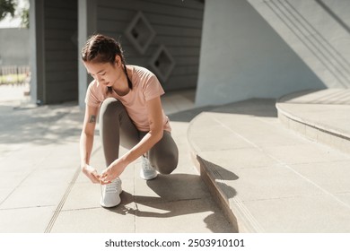 Active Asian woman tying shoelace on her running shoes. Preparation before jogging exercise. Fitness and sport activity. Healthy exercise concept - Powered by Shutterstock