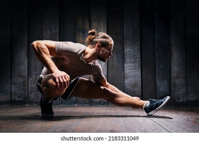 Active Athlete Do Exercises On The Floor, Intense Training On Black Background. Strong Sportsman In Sports Clothing Do Yoga. Fit Male Do Stretching Workout Indoor Training. Young Man Building Muscle.