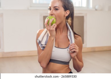 Active Athletic Sportive Woman With Towel In Sport Outfit Eating Apple After The Training