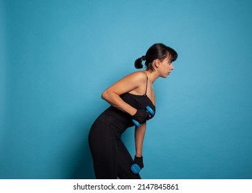 Active athletic trainer woman in sportwear training arm muscles practicing fitness exercices using dumbbells working at healthy lifestyle in studio. Concept of sport woman