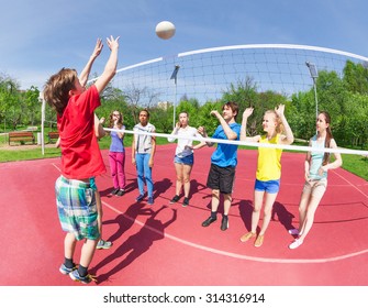 Active Boy And Girls Playing Volleyball On The Game Court Together Outside During Summer Sunny Day