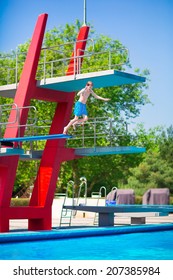 Active Brave Teenager Boy Jumping Into An Outdoor Pool From A High Tower With Spring Board Learning To Dive During Sport Class On A Hot Summer Day