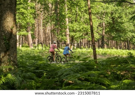 Active caucasian mature father and his daughter with bicycles riding outdoors in the forest