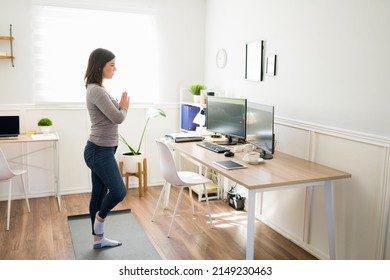 Active Caucasian Woman Standing In Front Of Her Desk At The Office While Working And Exercising With Yoga