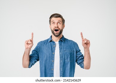 Active caucasian young man in denim clothes pointing upwards, offering sale discount at copyspace isolated in white background - Powered by Shutterstock