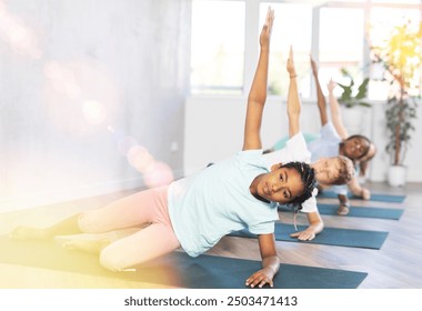 Active children exercising during yoga class in modern fitness center - vakrasana pose - Powered by Shutterstock