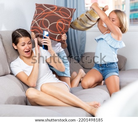 Active children with mom play pillows on the sofa at home