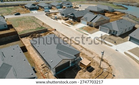 Active construction with materials staged across multiple lots, corner home driveway rebar lined forms framing at Highpointe Ranch along US 377, Blackjack Rd. Gray roofs, dirt piles in Aubrey, TX. USA