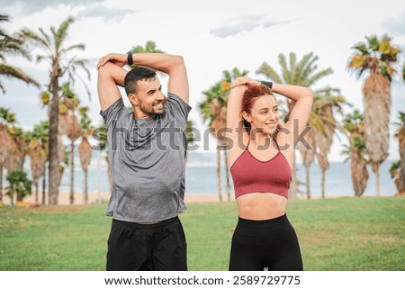 Active couple engaging in a refreshing and energizing stretching routine to enhance flexibility and promote overall fitness on the shoreline while enjoying each other company and motivation. High