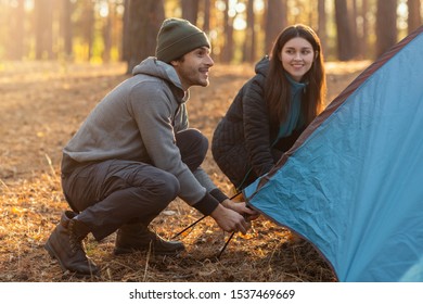 Active couple settle blue camping tent in the middle of autumn forest, having fun, copy space - Shutterstock ID 1537469669
