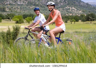 Active couple wearing helmets riding bikes in countryside together - Powered by Shutterstock