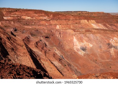 Active deep pit of red iron ore mine in Pilbara region in Western Australia with shadows of various levels