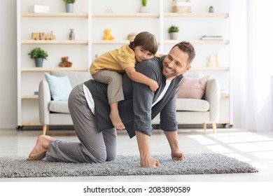 Active domestic games. Cheerful young man playing with his little son, piggybacking boy, happy kid playing cowboy on horse, smiling to camera at home interior
