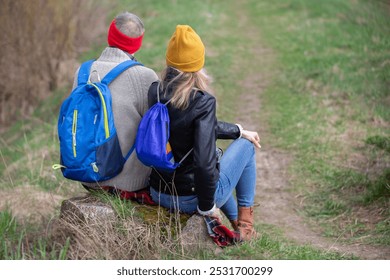 Active elderly Caucasian couple hiking with backpacks enjoying their adventure. They sit with their backs to the camera. - Powered by Shutterstock