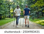 An active elderly couple engaging in a healthy walk on a forest path, using Nordic walking poles, promoting fitness and outdoor activity