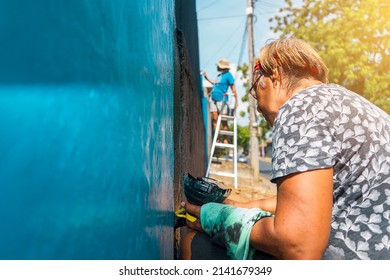 Active Elderly Latin Woman Working Outdoors Painting The Walls Of Her House