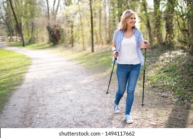 
Active elderly woman walks through nature with hiking sticks - Powered by Shutterstock