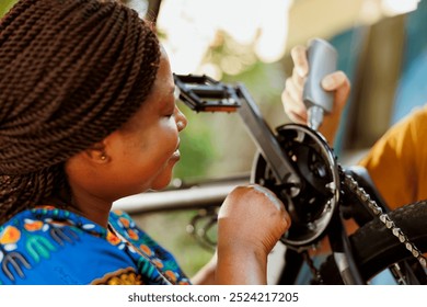 Active and enthusiastic black woman doing annual bike maintenance by making adjustments to pedals and checking gears in home yard. Using specialized tools boyfriend and girlfriend lubricating and - Powered by Shutterstock