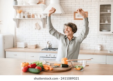 Active european senior old elderly woman grandmother dancing and singing while cooking preparing meal food dinner lunch vegetable salad at home kitchen - Powered by Shutterstock