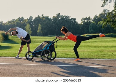 Active family with a child doing exercises and fitness in the morning outdoor. Running with a jogging stroller, squats , warm-up and healthy lifestyle