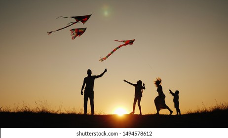 Active family with children launches kites in a picturesque place at sunset