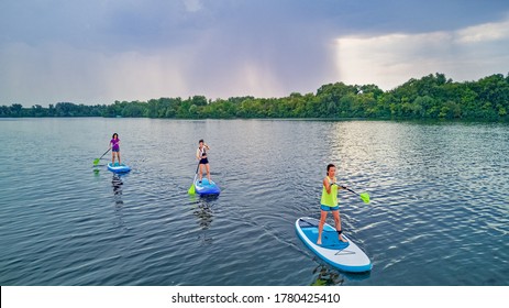 Active family on SUPs, standing up paddleboards, in river water, summer family sport, aerial top view from above
