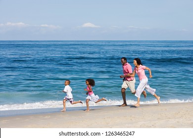 Active family running along sandy beach summer vacation