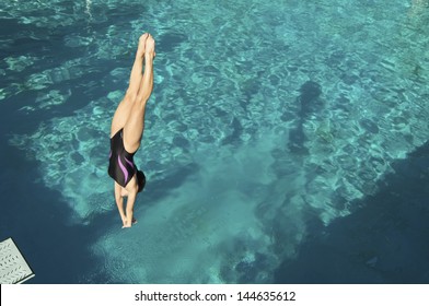 Active female diver diving upside down into the swimming pool