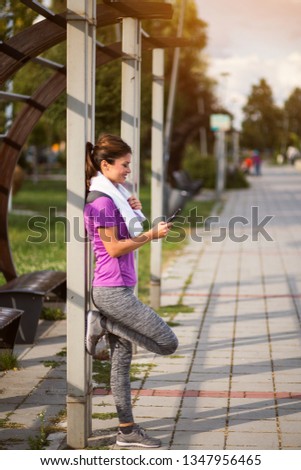 Active female jogger resting and using smartphone	