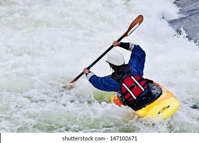 an active female kayaker rolling and surfing in rough water