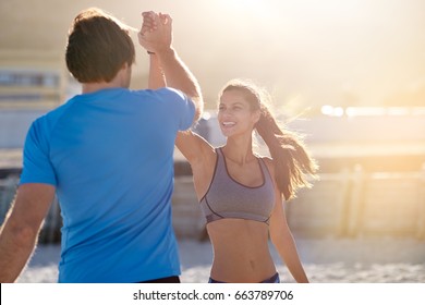 Active fit friends couple high five in celebration after completing their gruelling exercise workout run, golden sun flare behind - Powered by Shutterstock