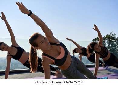 Active Fit Healthy Sporty Young Adult Diverse Women Only Friends Stand In Yoga Pose Side Plank At Active Outdoor Group Class Do Fitness Exercise Stretching In Balance Together At Retreat Workout.